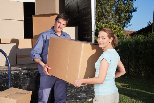 Professional movers carrying boxes through a flat corridor in Redbridge